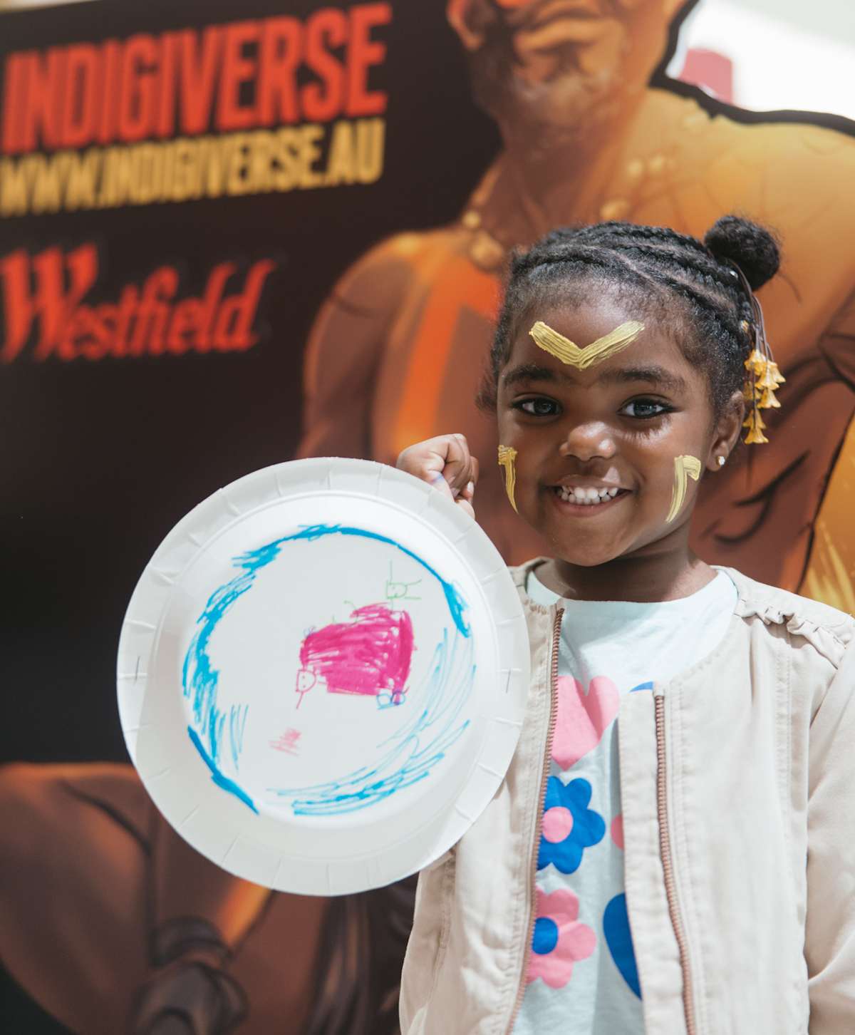 An image of a girl holding a NAIDOC art shield. 