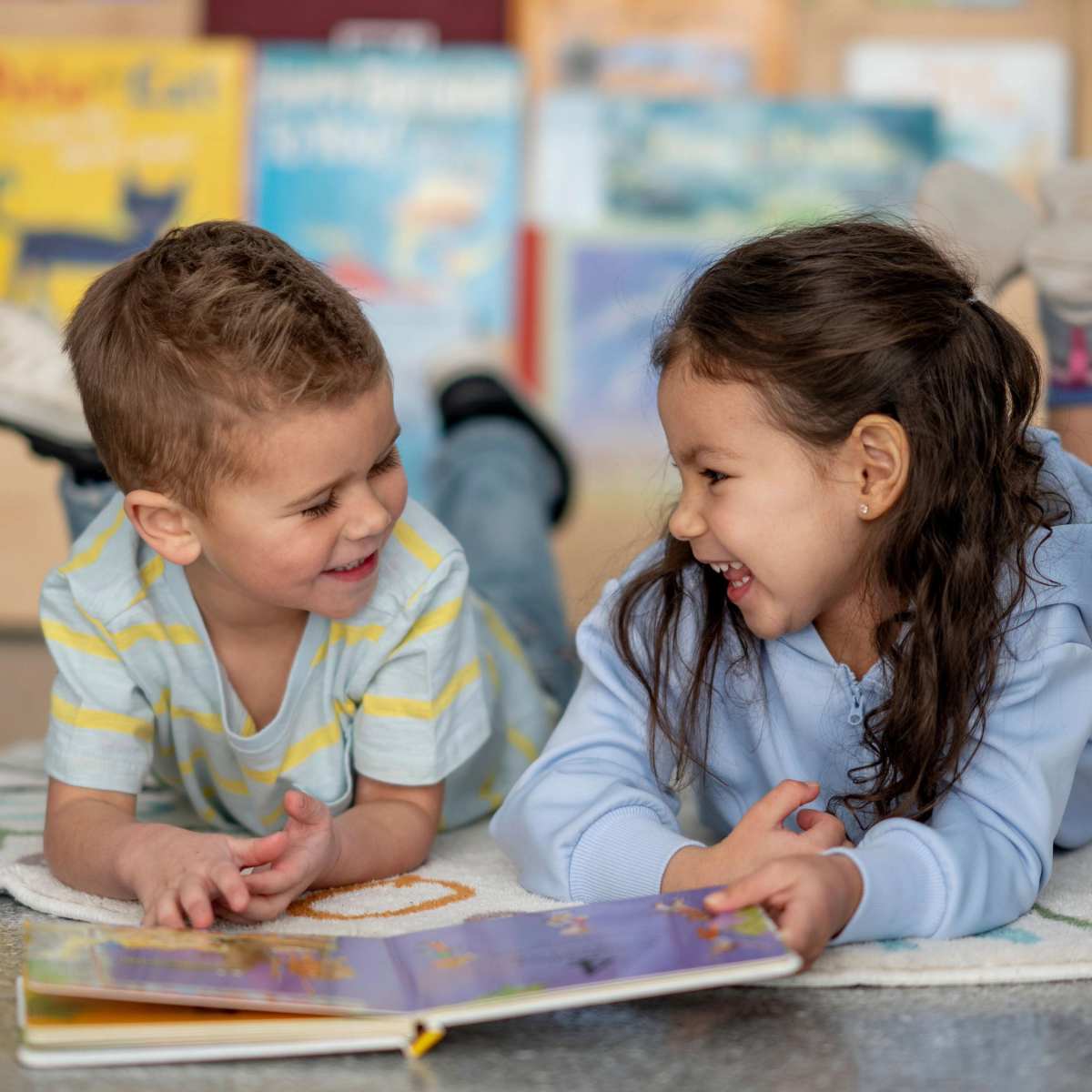 Boy and girl laughing while reading a book