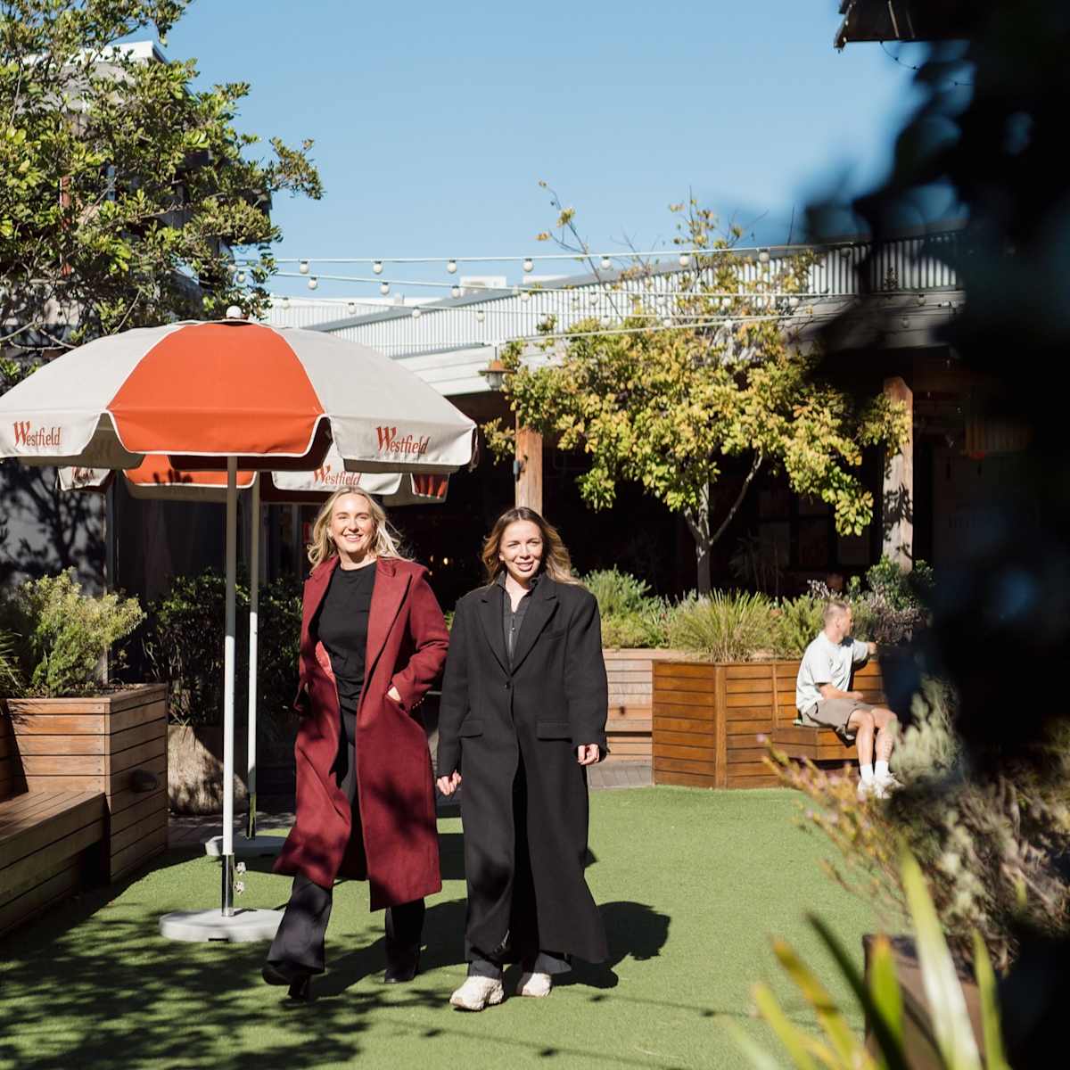 two women walking in coats on the rooftop