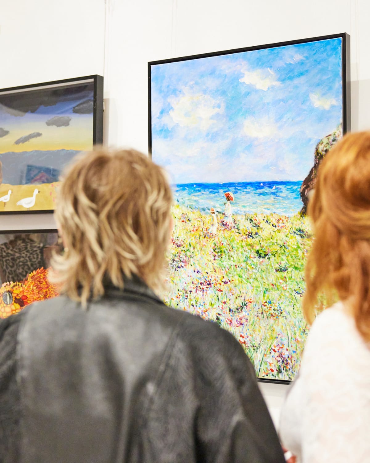 Photo of two customers admiring a painting.