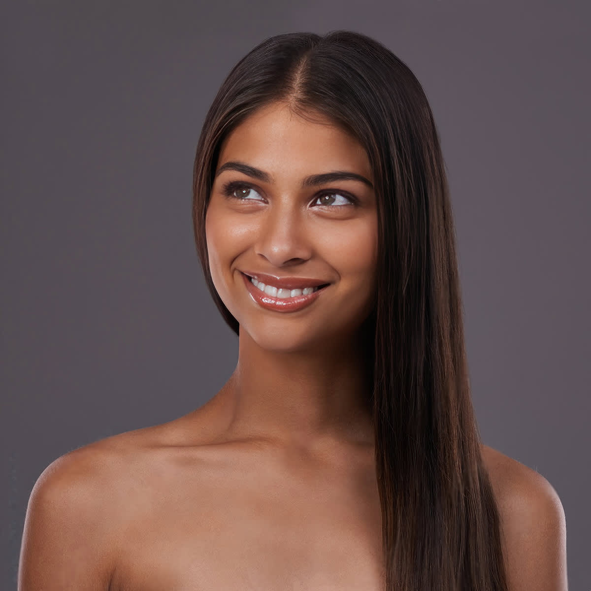 Female smiling against a grey background.