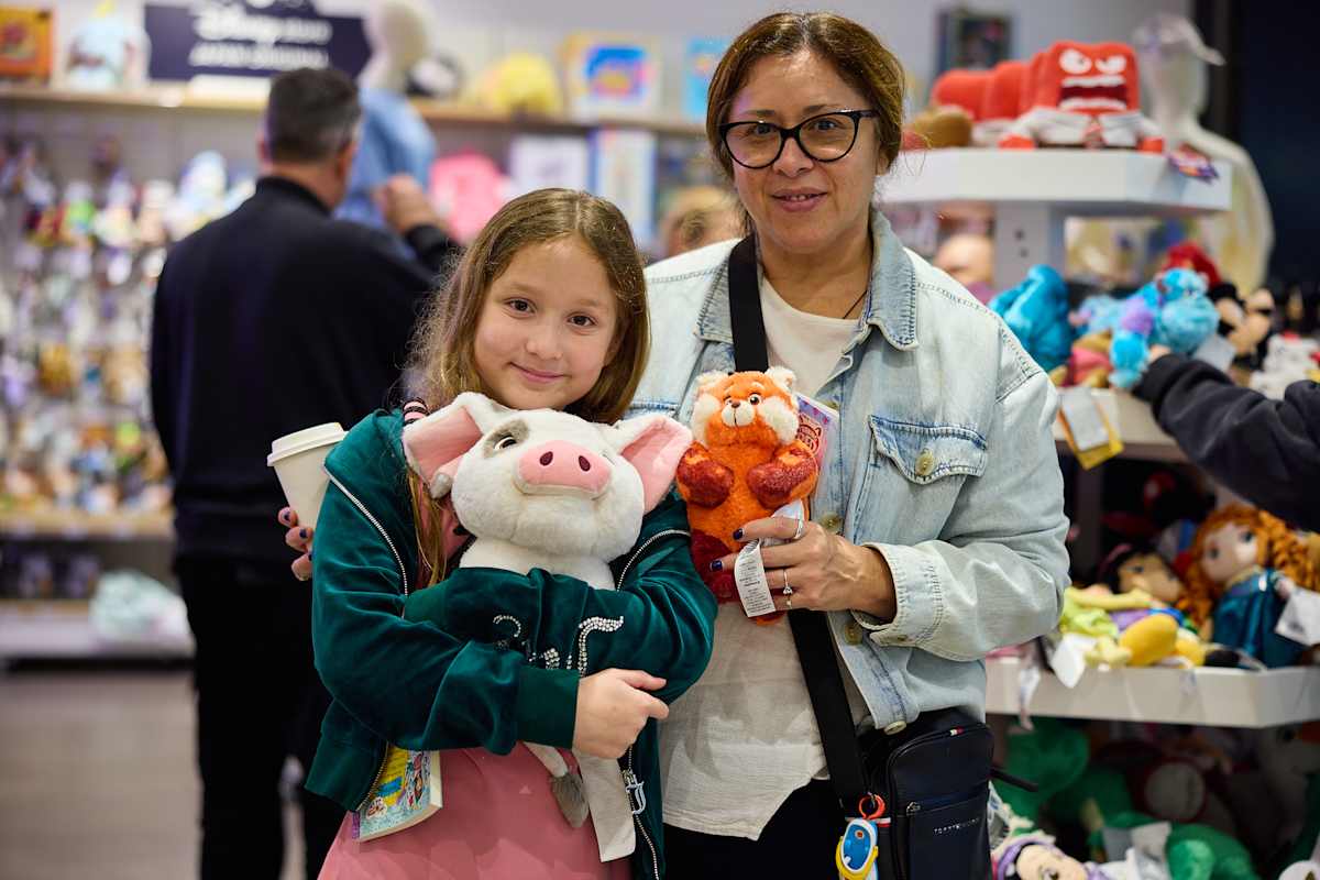 A mother and child at the Disney Store, holding plush toys.
