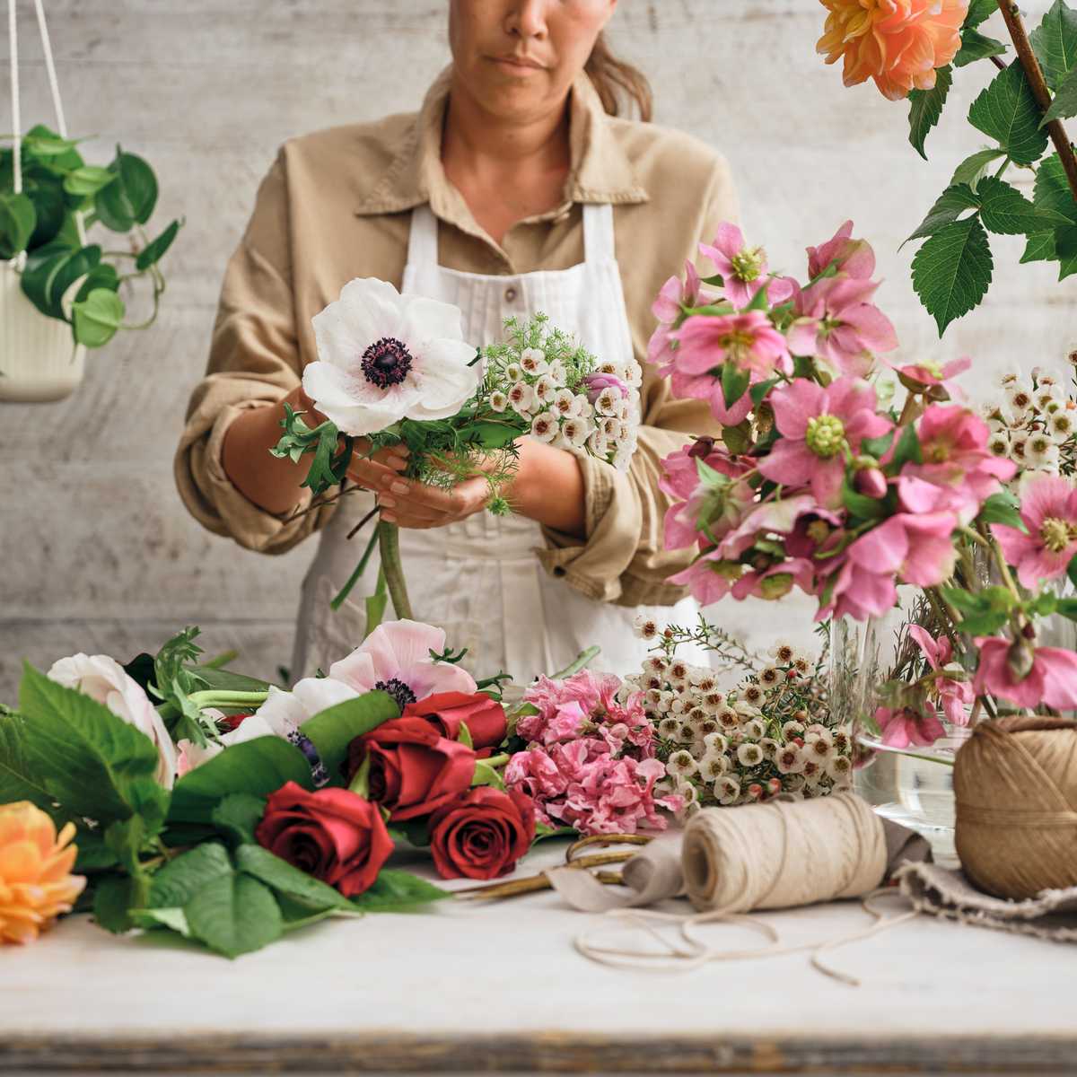 A bouquet of Sweet Lily Co flowers being put together by a florist, whites and pinks