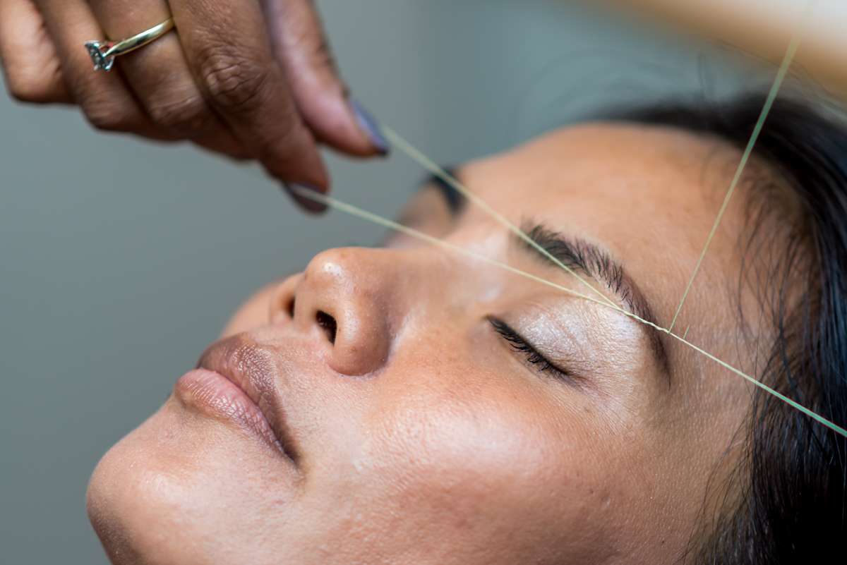 women getting eyebrows threaded