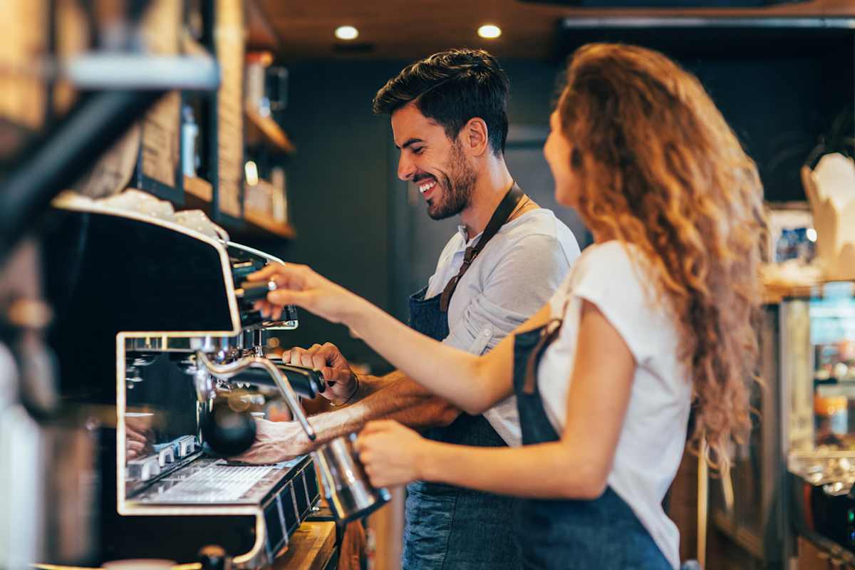 Man and women laughing while making coffee