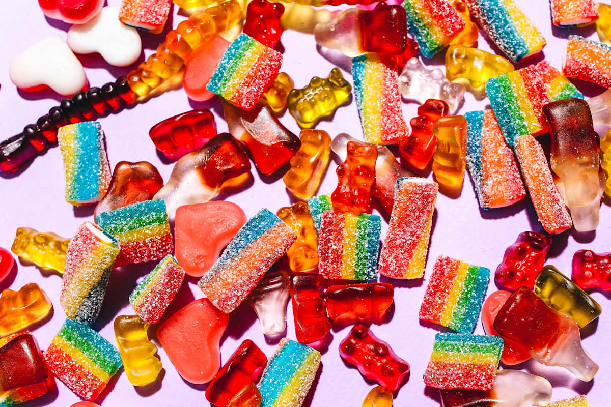 Assorted lollies and candies on a pink background. 