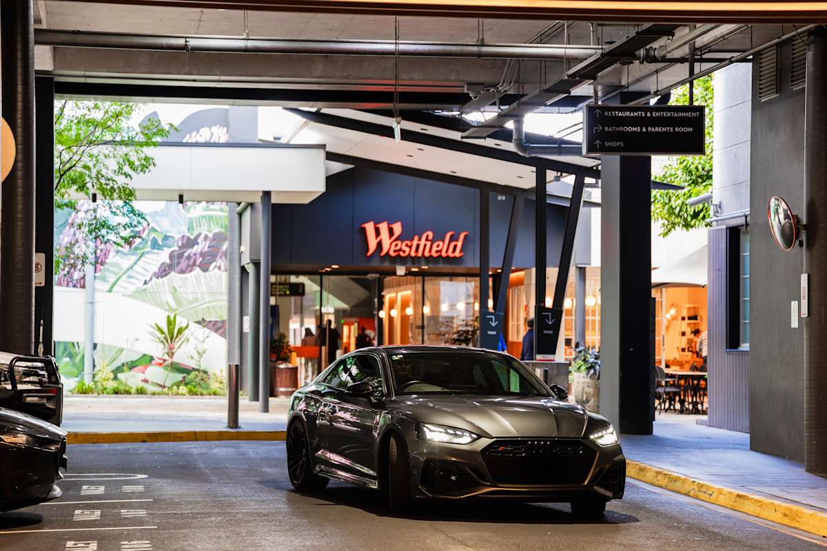 Car being driven in a car park with the red Westfield logo in the background.