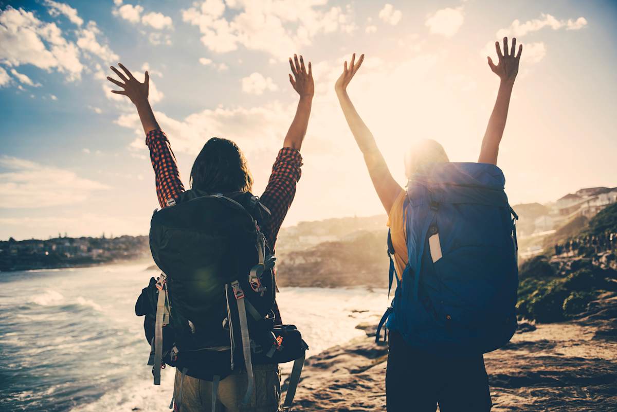 Two people travelling with their hands in the air