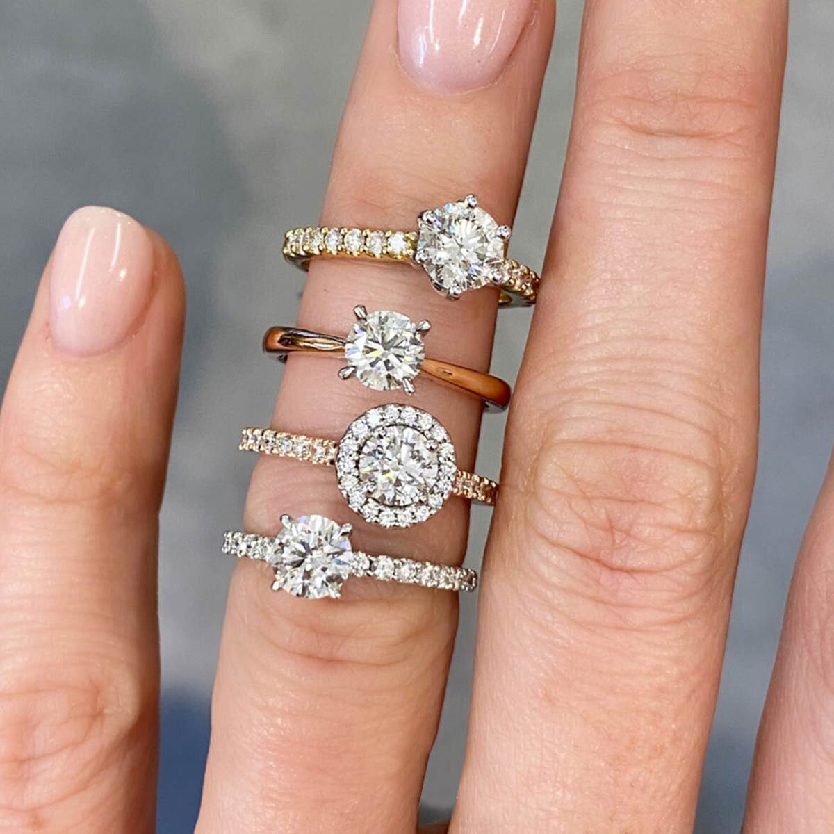 A woman's hand wearing 4 engagement rings