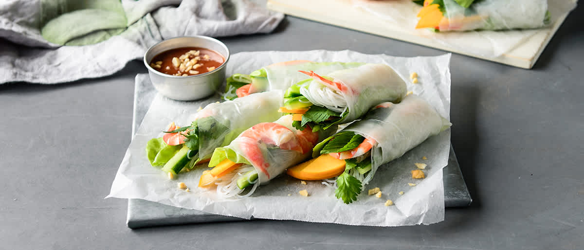 Image of two rice paper rolls sitting on a concrete food board