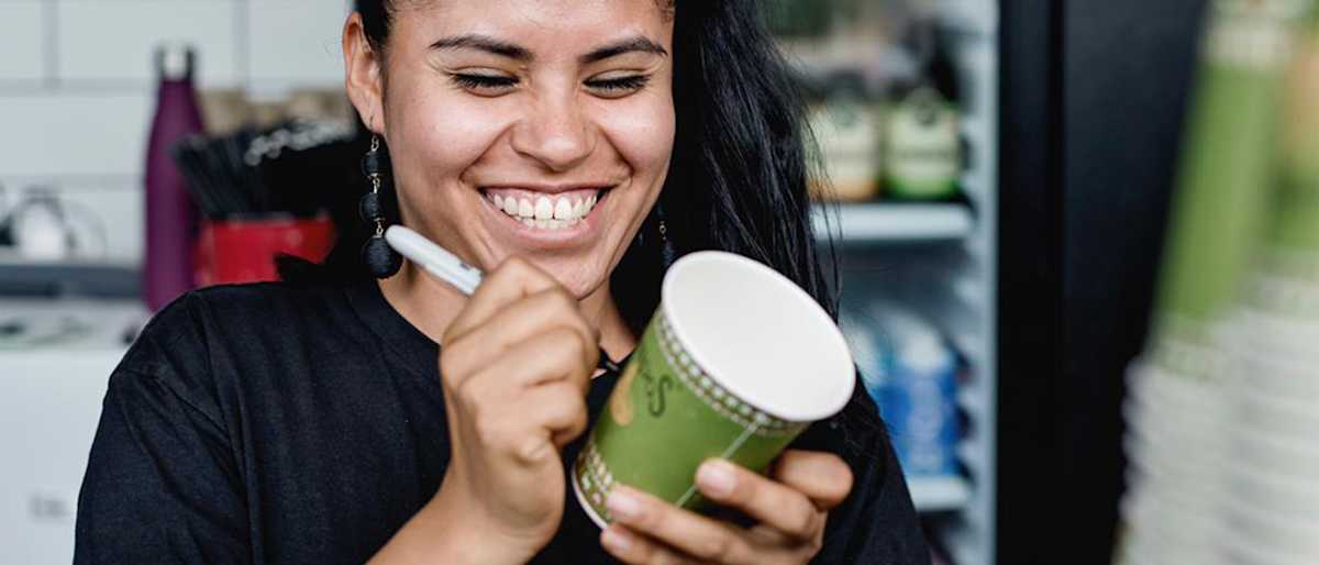 Cafe worker writing on a coffee cup