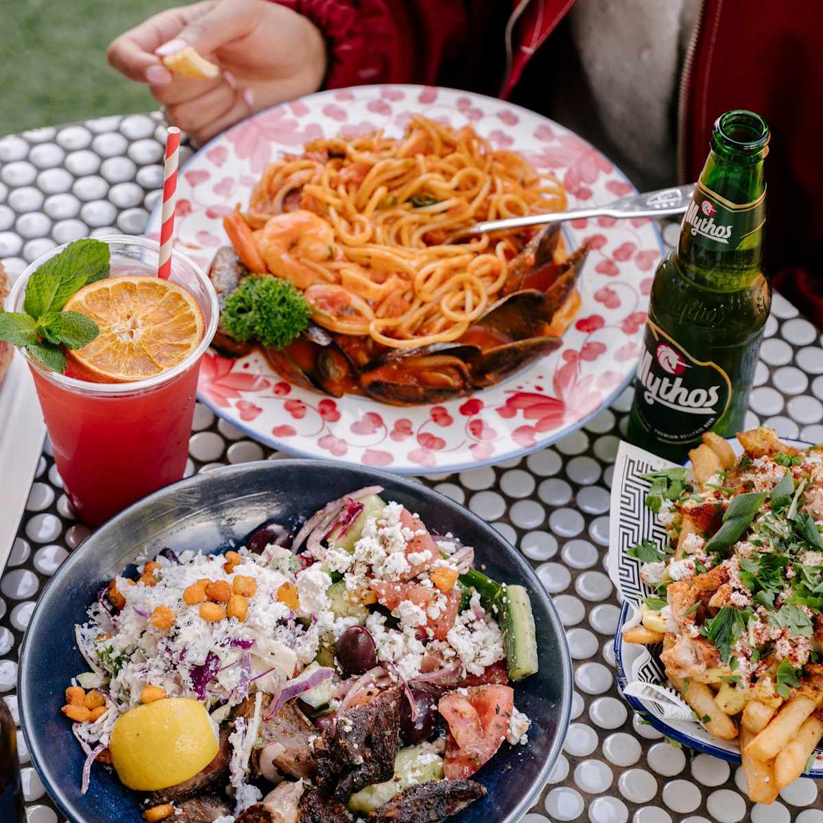 close up image of rooftop table with crinitis pasta & zeus bowl with 2 drinks