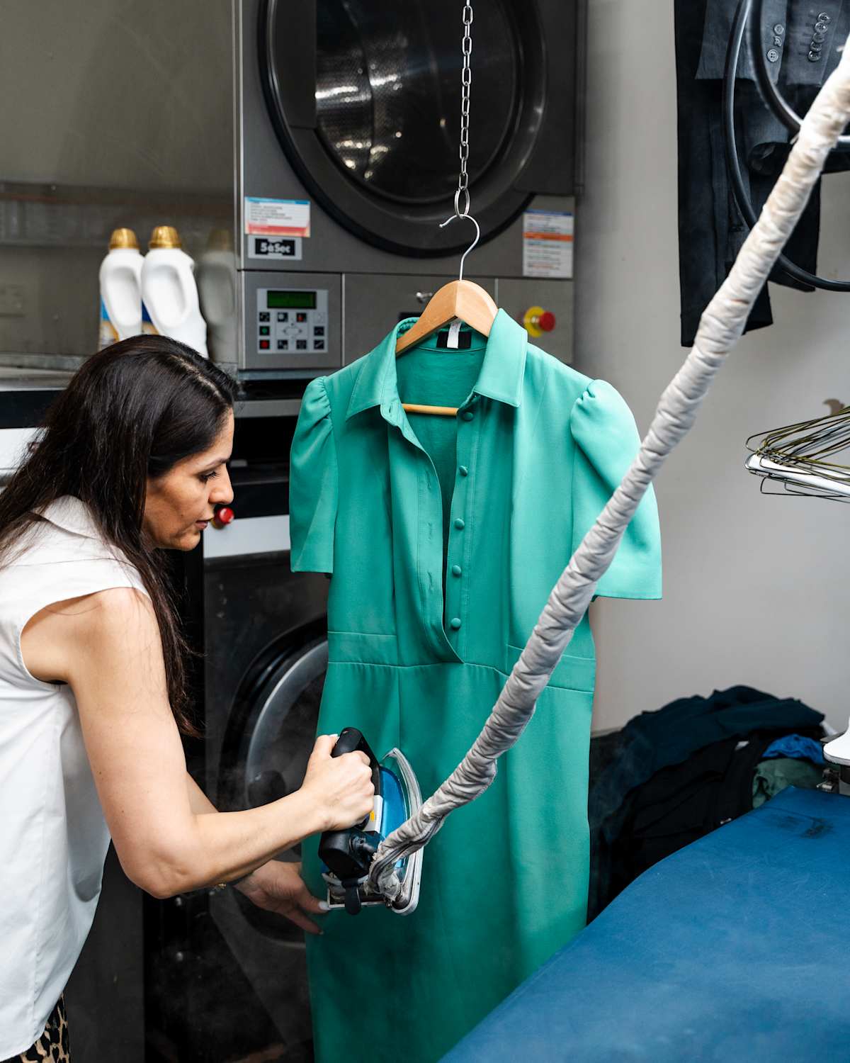 A lady steam ironing a green dress