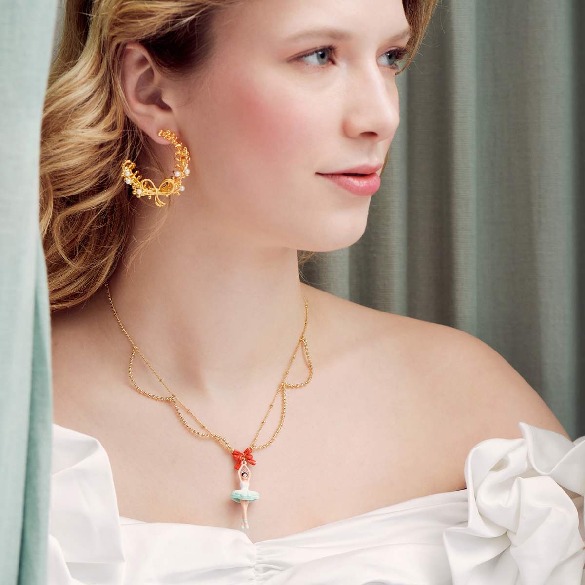 Close up of woman wearing gold earrings and ballerina necklace