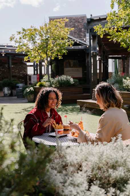 two women sitting on the rooftop dining with food. HunterHunter image 2024