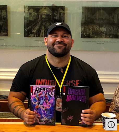 Picture of Scott Wilson, comic creator, holding two comics in his hands. 
