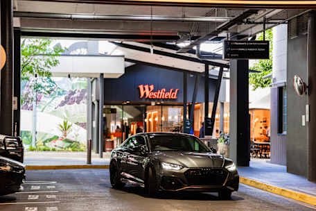 Grey car driving into Valet parking with the Westfield logo in the background.