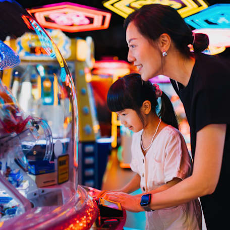 Mother and daughter playing games in an arcade