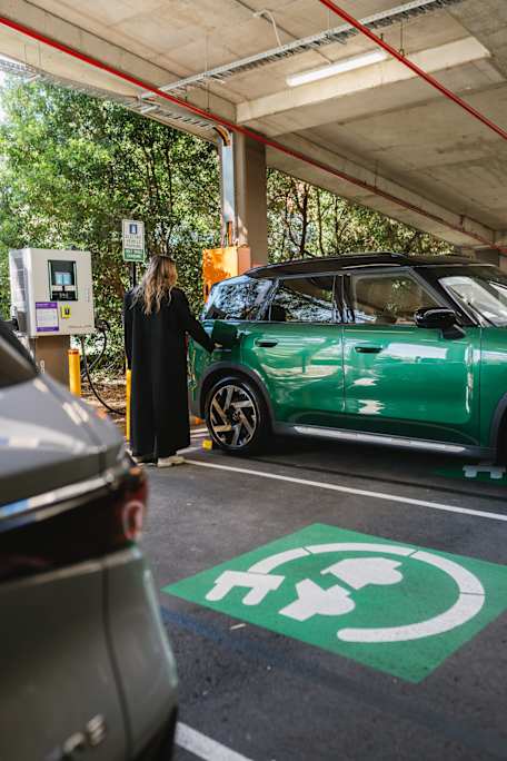 Woman charging green EV car at the EV charging station in Westfield Kotara