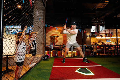 man in batting cage and 2 children watching from outside Ballpark Kotara